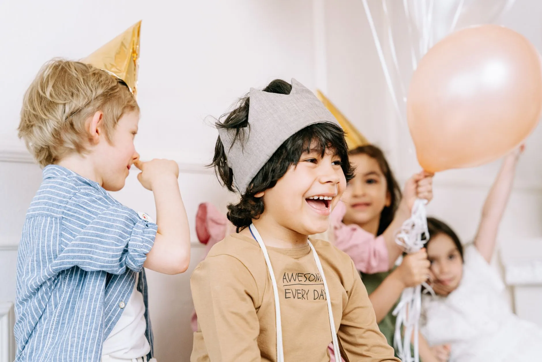Niños celebrando con gorros y globos de fiesta